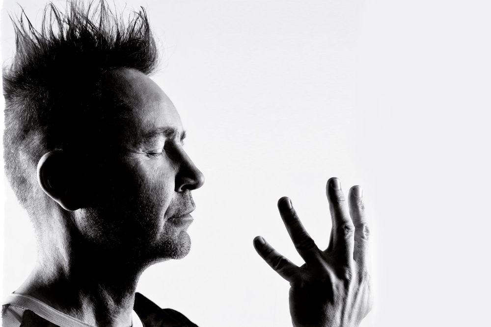 Czarno-biały portret artysty. W ujęciu prawy profil mężczyzny w stanie koncentracji , na co może wskazywać wyraz twarzy oraz zamknięte oczy. Przed twarzą rozłożona dłoń z palcami wyprostowanymi ku górze w charakterystycznym ułożeniu podczas trzymania gryfu skrzypiec. NA zdjęciu brak jednak tego instrumentu.