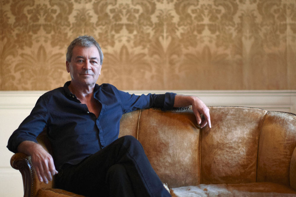 Fotografia przedstawia siedzącego na sofie Iana Gillana – lidera grupy Deep Purple