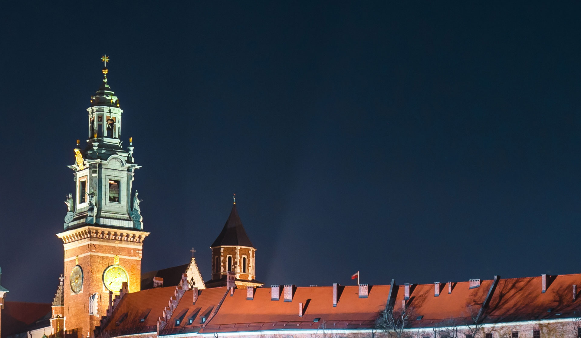 Zdjęcie tytułowe przedstawiaoświetloną wieżę katedry wawelskiej na tle nocnego nieba